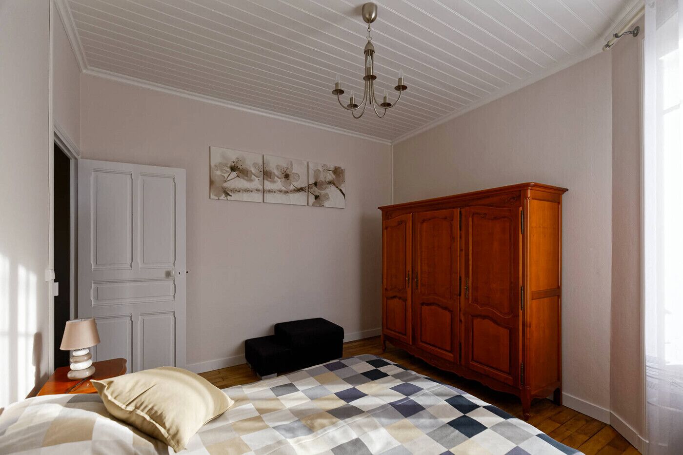 Ein Schlafzimmer mit einem Bett, einem Holzschrank, einer Lampe und einem Bild an der Wand.