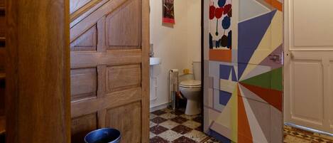Un baño con piso de baldosas, inodoro y zona de ducha.