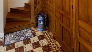 Eine Holztreppe mit Handlauf, ein blauer Mülleimer und ein gemustertes Teppich im Fußboden.