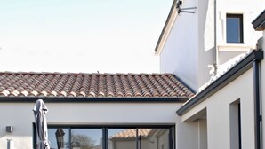 Eine Terrasse mit Tisch, Stühlen, einem Grill und einem Poolbereich mit Liegestühlen.