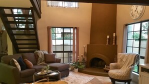 Un salon chaleureux avec une cheminée, un canapé, un fauteuil et une table basse.