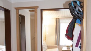 A hotel room with a wooden floor, a mirror, a wheelchair, a pair of shoes, and a coat rack with a helmet. - Vacation apartment Chiemsee, 65sqm, terrace, 1-5 persons (Übersee)