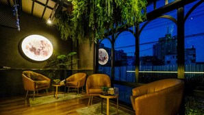 A room with a large window, a round moon-like light fixture, and three leather chairs. - U Sabai Hotel (Bangkok)