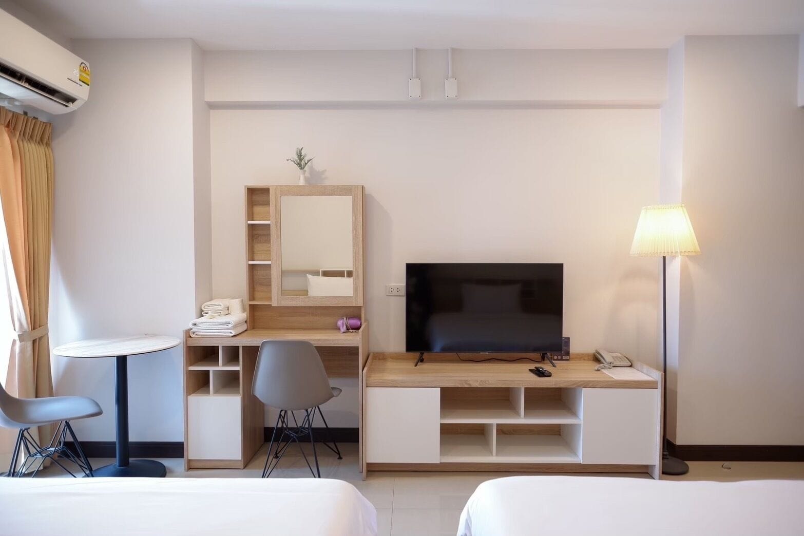 A hotel room with a bed, a desk with a chair, a TV, and a lamp.