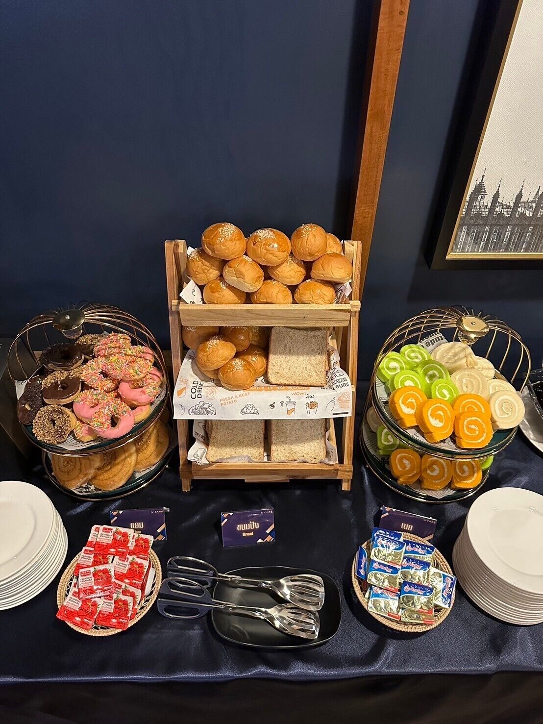A buffet table with various food items including donuts, bread, and pastries.