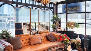 A modern interior with a leather sofa, decorative lamps, and a view of the city through large windows. - U Sabai Hotel (Bangkok)