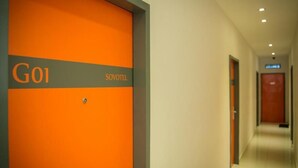 Un couloir avec un mur orange et une porte portant les inscriptions « G01 » et « SOVOTEL ».