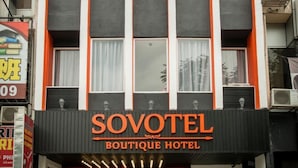 L’extérieur du Sovotel Boutique Hotel se distingue par son enseigne bien visible, ses grandes fenêtres et ses unités de climatisation.