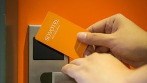 Une main insérant une carte dans un lecteur de cartes.