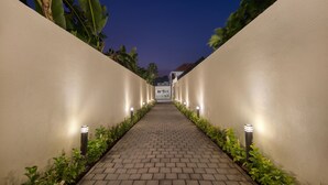 A paved pathway flanked by walls with embedded lights, leading to a building entrance. - The Grand Daha Luxury Villas (Seminyak)