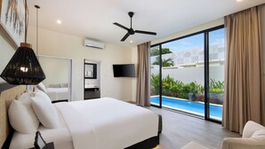A modern hotel room with a large bed, a flat-screen TV, a ceiling fan, and a view of a swimming pool. - The Grand Daha Luxury Villas (Seminyak)