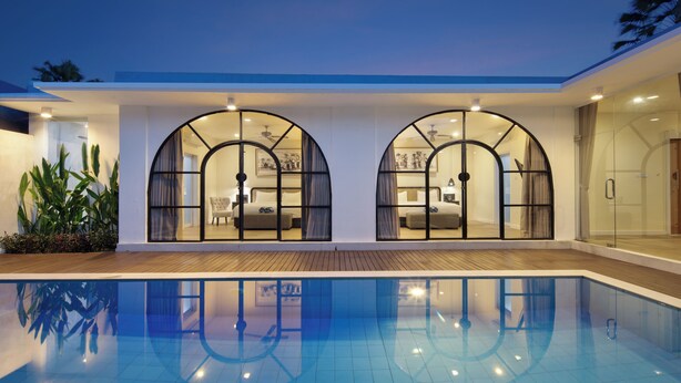 A modern hotel with a swimming pool, large arched windows, and a well-lit interior. - The Grand Daha Luxury Villas (Seminyak)