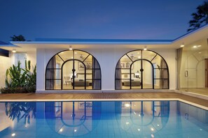 Un hotel moderno con piscina, amplias ventanas en arco e interiores bien iluminados.