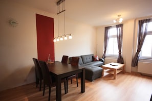 Una sala de estar moderna con una mesa de comedor, sillas, un sofá y una mesa baja.