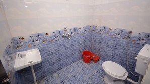 A bathroom with a blue marble floor, a white sink, a toilet, and a shower. - Hotel Kashi Khand (Varanasi)