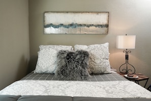A bed with patterned bedding, a fluffy pillow, a wall-mounted abstract painting, and a bedside table with a lamp. - Beautifully Updated Home!
Close to Dickies, Stockyards & TCU
Family/Pet friendly (Westworth Village)