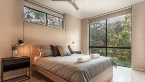 A modern bedroom with a large bed, two bedside tables, a ceiling fan, and large windows offering a view of trees. - Carpe Vino - Peaceful Bushland Luxury Between Coast and Town (Margaret River)