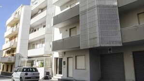 Ein mehrgeschossiges Wohngebäude mit Balkonen, einer Garage und einem heruntergelassenen Rolltor.