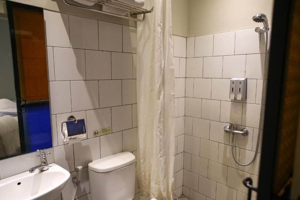 Une salle de bain avec un lavabo, des toilettes et une douche, le tout de couleur blanche.