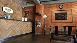 Un área de recepción con pared de madera en patrón de espiga, pared de ladrillo con una obra de arte de motocicleta, un reloj y un banco.