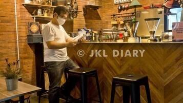 A café interior with a brick wall, wooden counter, and bar stools.