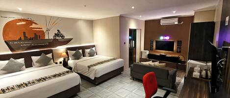 A hotel room with two beds, a desk, a TV, and a wall with a cityscape mural.