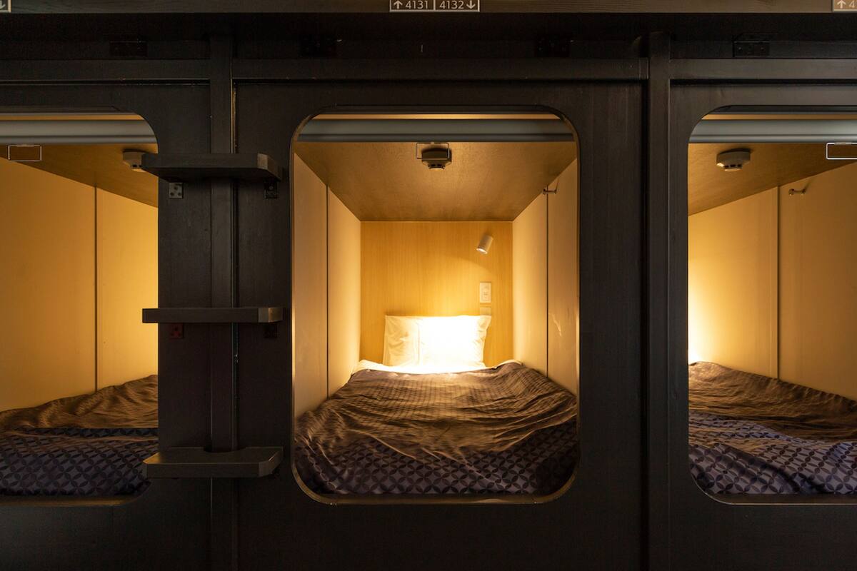 A train compartment with two beds, each with a patterned blanket and a pillow.