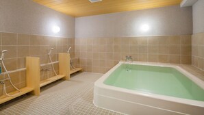 Kylpyhuone, jossa on suuri kylpyamme, puiset penkit ja laatoitetut seinät.