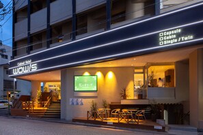Um hotel com fachada moderna, um painel digital e área de estar ao ar livre.