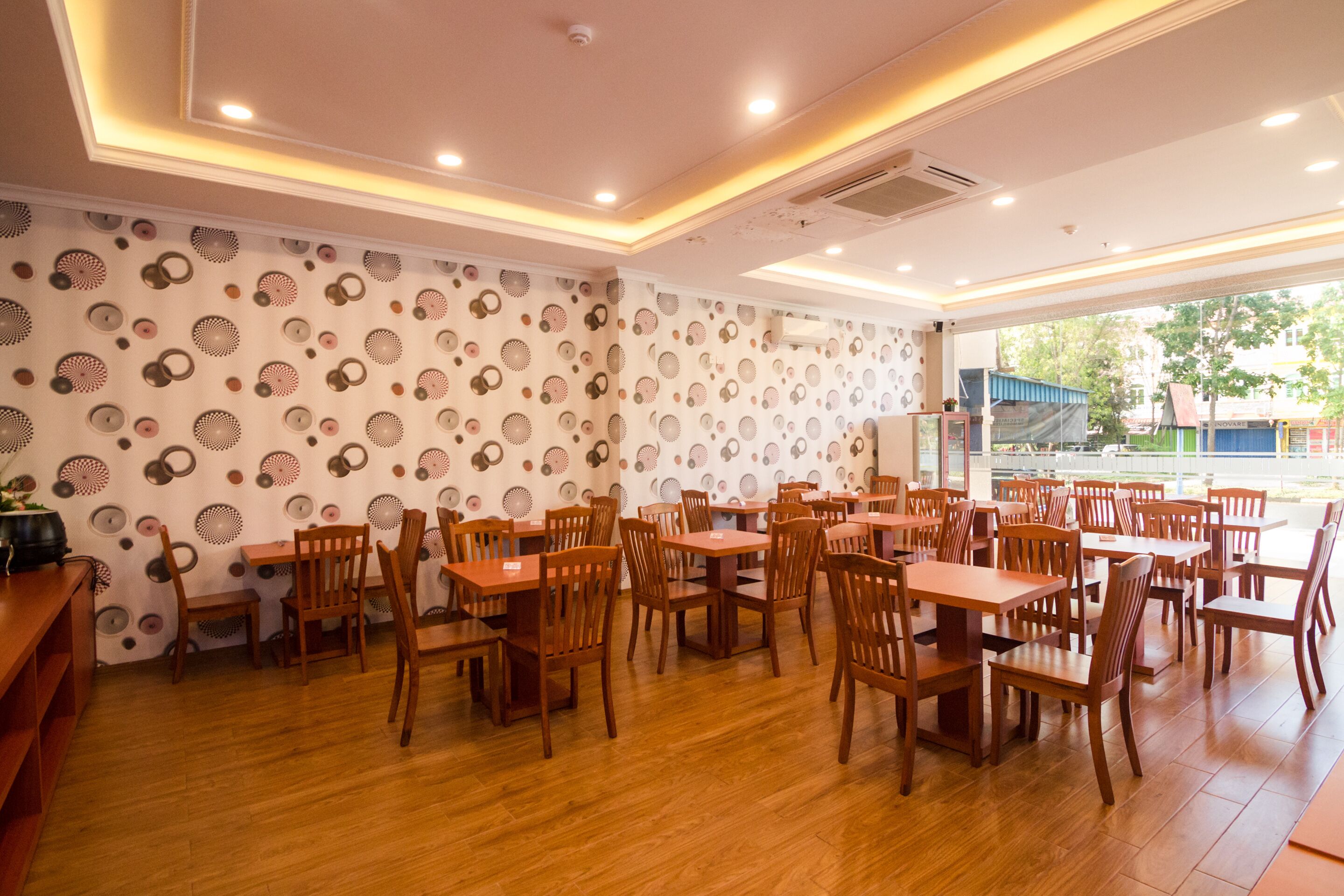 A restaurant with wooden tables and chairs, patterned wallpaper, and a view of the outside.
