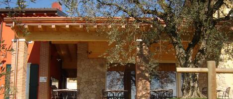 A building with a stone facade, a wooden pergola, and outdoor seating.