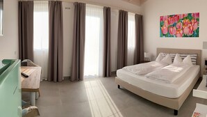 A bedroom with a bed, a desk, and a chair. There are curtains on the windows. - Agriturismo Le Tese (Lazise)