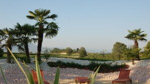 A beach area with palm trees, a sandy beach, and a row of wooden lounge chairs. - Agriturismo Le Tese (Lazise)