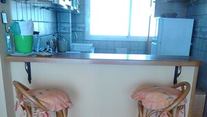 A kitchen with two wooden bar stools, a countertop, and a window.