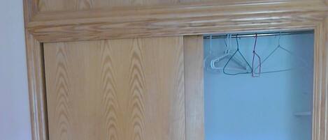 Un armario de madera con puerta espejada y una repisa pequeña.