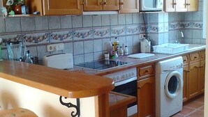 A kitchen with wooden cabinets, a microwave, a washing machine, and a tiled backsplash.