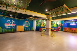 A room with a mural, a wooden table with chairs, and a ceiling fan.