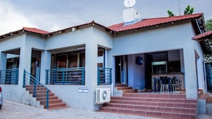A building with a reception area, a staircase leading to the entrance, and a sign indicating a restaurant named 'ROSEVILLE'. - Rose Villa Lodge (Kitwe)
