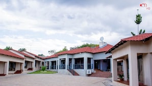 A courtyard with buildings featuring red-tiled roofs and a satellite dish. - Rose Villa Lodge (Kitwe)