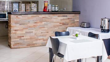 Un espace repas moderne avec un îlot central en pierre, des nappes blanches et des chaises.