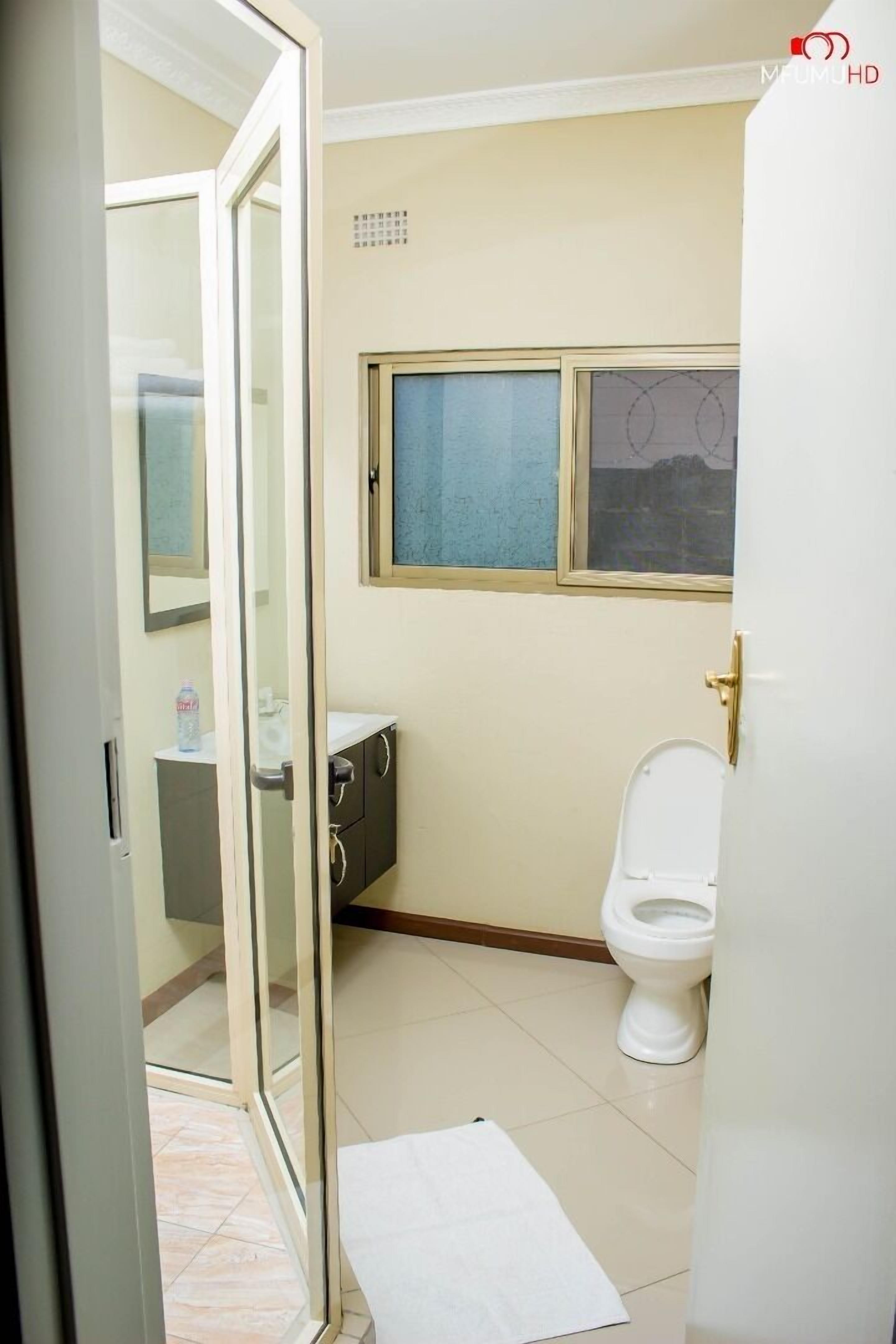 A bathroom with a toilet, a sink, and a window.