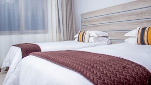 A hotel room with two beds, a wooden headboard, and a window with curtains. - Rose Villa Lodge (Kitwe)