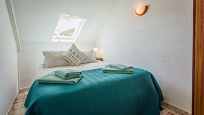 Ein Schlafzimmer mit Bett, Fenster und Wandleuchte.
