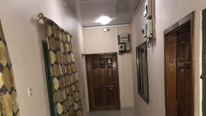 A hallway with patterned curtains, a wooden door, and a tiled floor. - Ricardo's property (Accra)