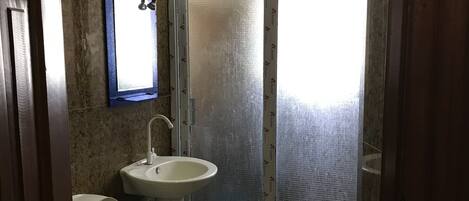Une salle de bain comprenant des toilettes, un lavabo et un espace douche.