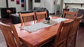 Una mesa de madera para comer con un camino de mesa de encaje, rodeada de sillas de madera.