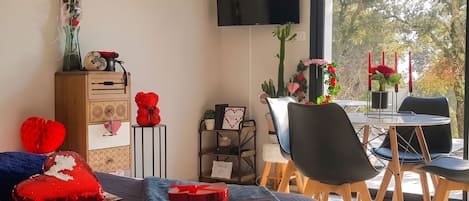 Un dormitorio moderno con cama, cómoda, televisor y un comedor con mesa y sillas.