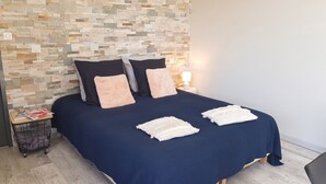 A bed with a dark blue bedspread, two pillows, and a white decorative pillow. - Homerez - House in Mornas (Mornas)
