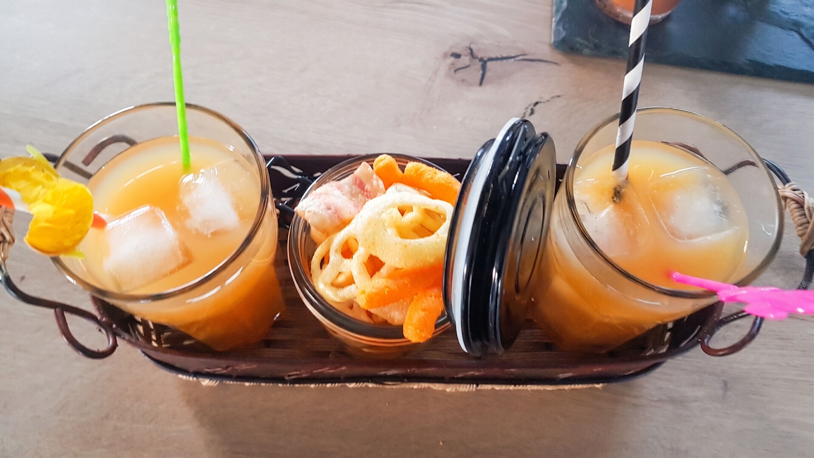 A tray with three glasses of iced tea, each with a straw and a slice of fruit.