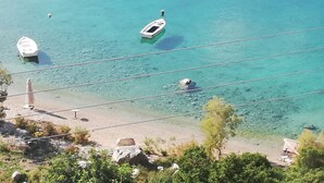 A coastal view with clear turquoise waters, a sandy beach, and a few boats anchored nearby. - MAMMA MIA ON THE BEACH (Pefkali)